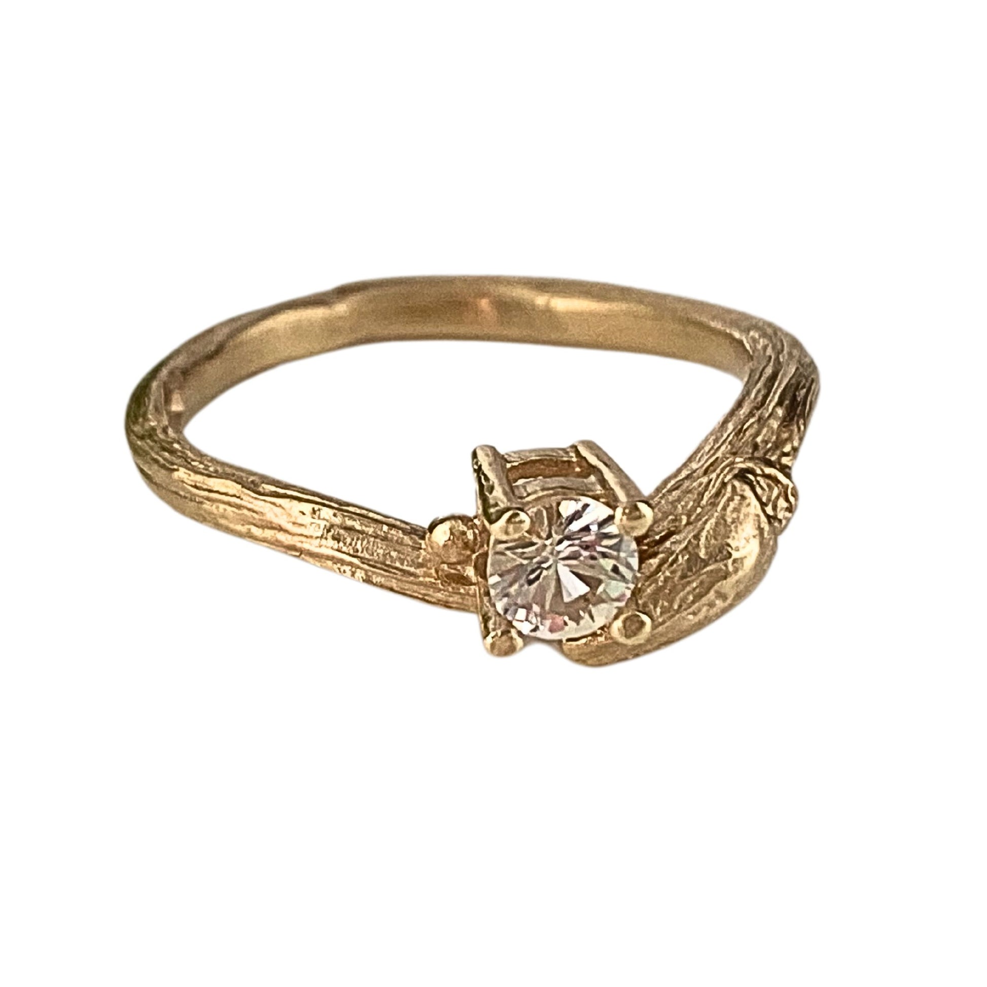 Cast from a real willow twig in 9ct gold, showing the willow bud and bark details, this nature inspired twig ring is set with a brilliant cut natural white sapphire