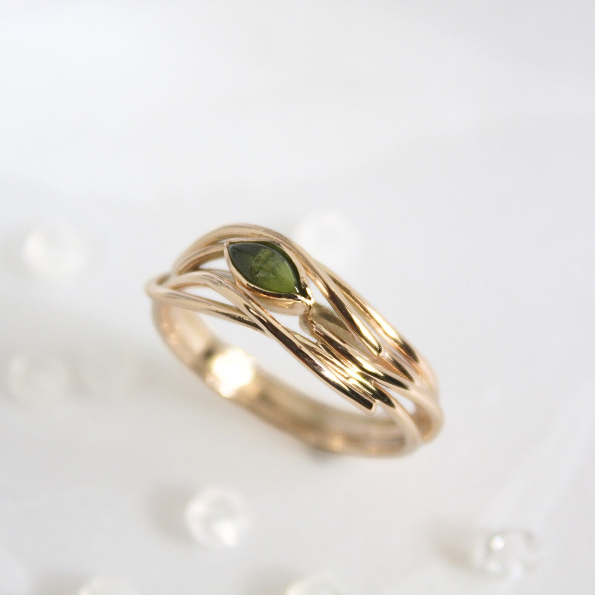 Unique entwined gold infinity ring set with a marquise natural gemstone.