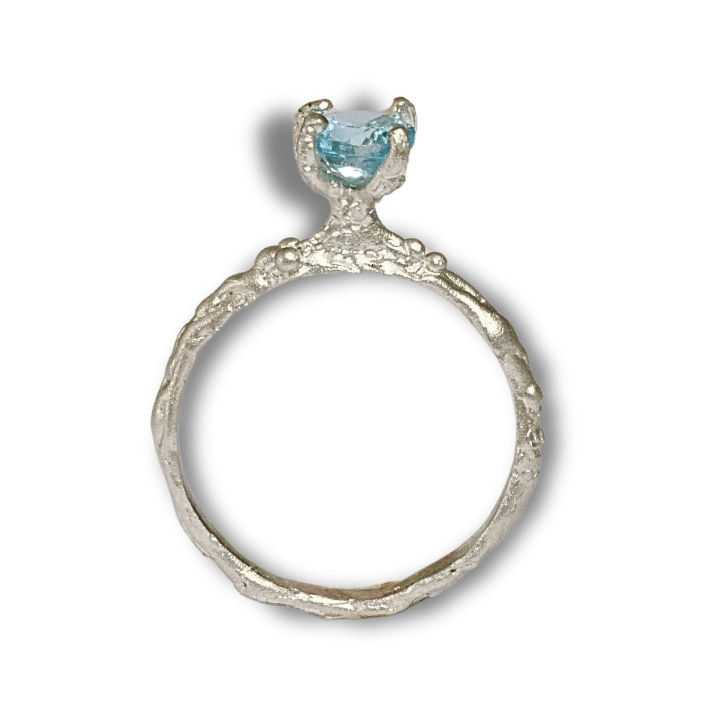 Rustic style high set ring with four claws holding a round faceted blue topaz.