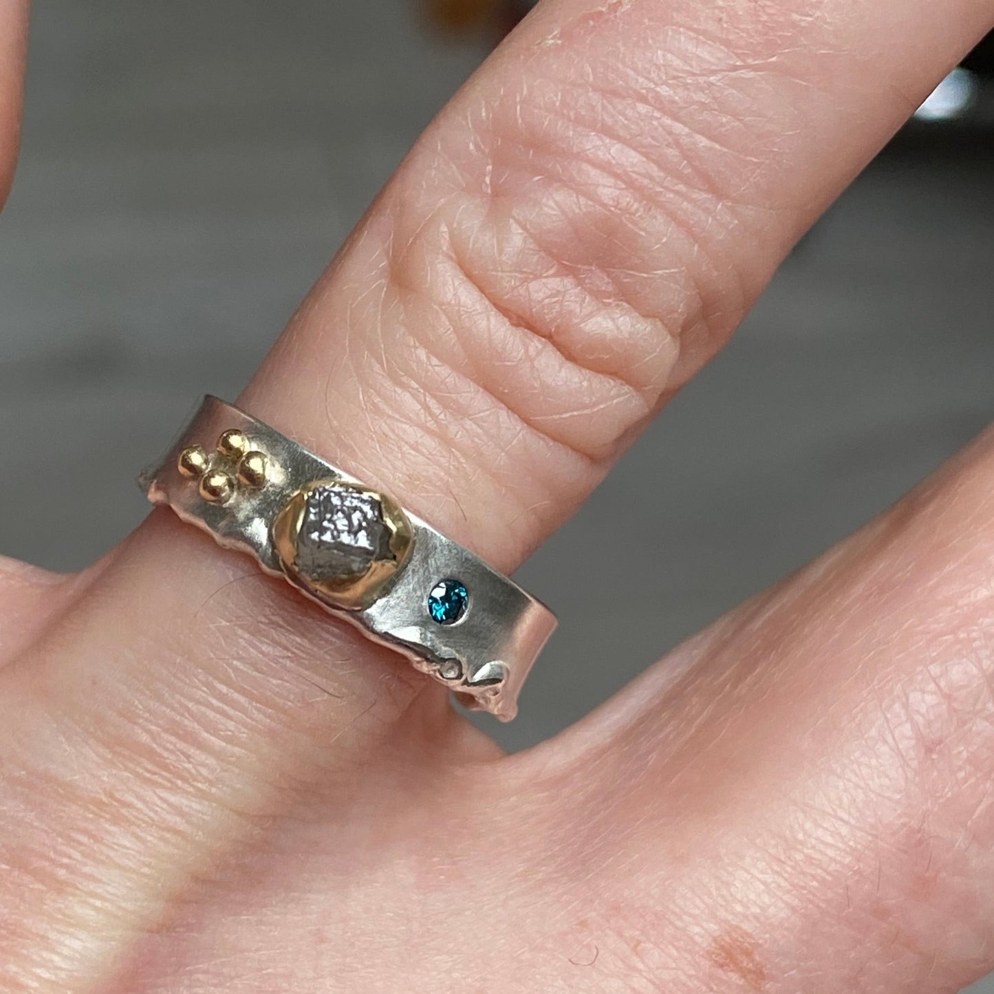 Rough Natural Grey diamond band ring. Sterling silver band set with a natural raw uncut diamond in 18ct yellow gold and a blue brilliant cut diamond. Alternative engagement or wedding ring.